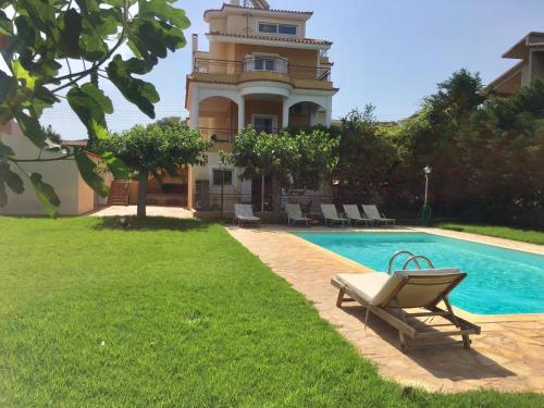 une maison avec une piscine à côté d'un bâtiment dans l'établissement Relaxing Villa with Swimming Pool and Garden, à Áyios Yeóryios