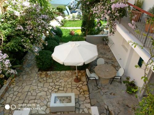 a patio with a table and a white umbrella at Waterside Apartments in Ayia Evfimia
