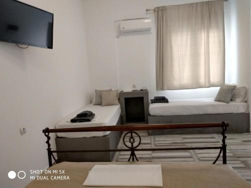 a room with two beds and a flat screen tv at Waterside Apartments in Ayia Evfimia
