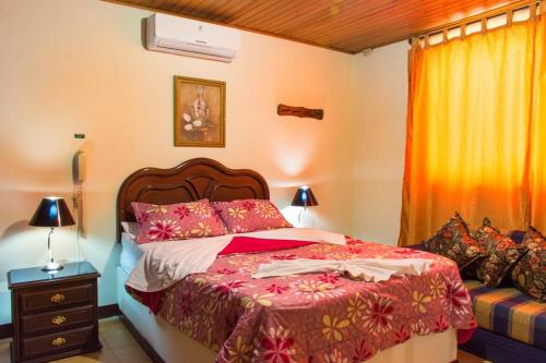 a bedroom with a bed with a red comforter at Hotel D' Oscar in Cali