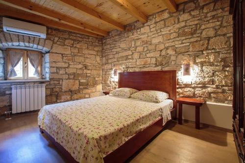 sypialnia z łóżkiem i kamienną ścianą w obiekcie Didova Villa in the Heart of Istria w mieście Jakići