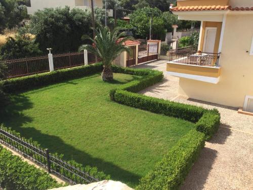 a yard with a green hedge in front of a building at Relaxing Villa with Swimming Pool and Garden in Áyios Yeóryios