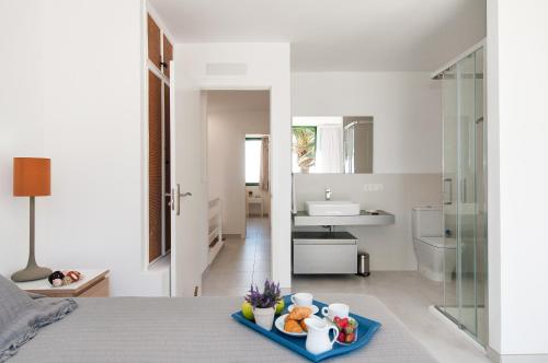 マスパロマスにあるBeachfront Apartment Las Burras FA03の白いベッドルーム(ベッドに食料品のトレイ付)