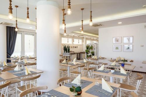 un comedor con mesas, sillas y ventanas en Hotel Nobel, en Gabicce Mare