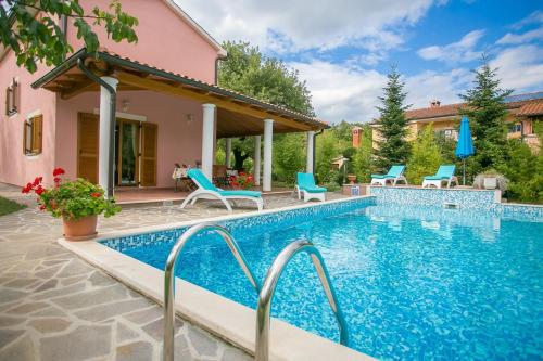 uma piscina com cadeiras azuis e uma casa em Pleasant Villa Valmonida with Pool, Sauna, Gym and BBQ em Žminj