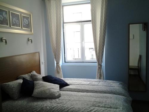een slaapkamer met een groot bed en een raam bij Baixa GuestHouse in Lissabon