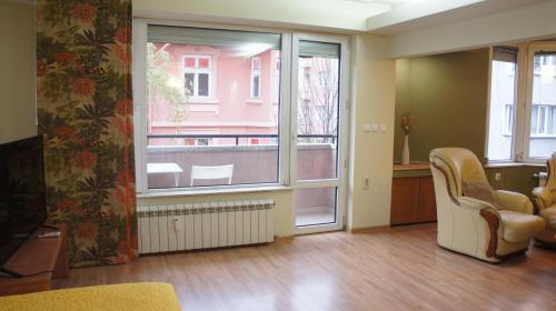 a living room with a chair and a window at Vitosha Apartments in Sofia
