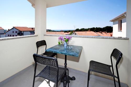 a small table on a balcony with chairs and flowers at Apartments Beakovic in Poreč
