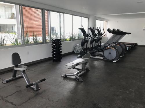 a gym with several tread machines and chairs in a room at Metropolitan Suites in Guadalajara