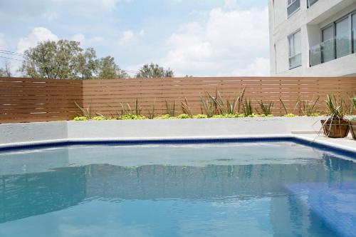 a swimming pool in a backyard with a wooden fence at Metropolitan Suites in Guadalajara