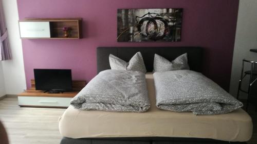 ein Bett mit drei Kissen und einer lila Wand in der Unterkunft Haus Linde Frauenwald am Rennsteig in Frauenwald