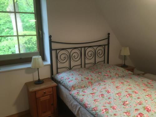 a bedroom with a bed with a floral bedspread and two lamps at Ferienglück Lindwedel in Lindwedel