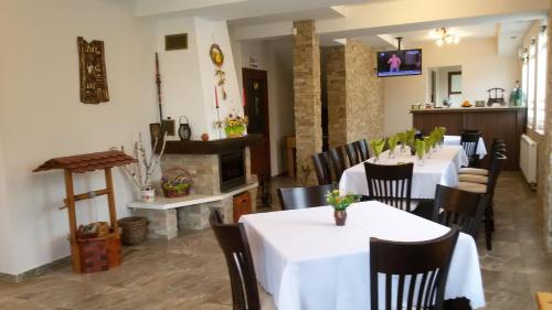 a restaurant with white tables and chairs and a fireplace at Къща за гости ДАЯНИЦА in Kopilovtsi