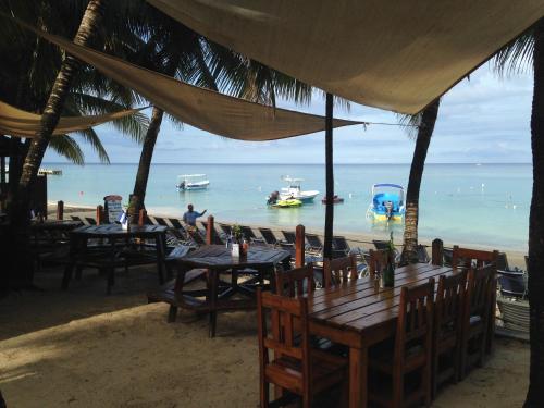 a restaurant with tables and chairs on the beach at Bananarama Dive & Beach Resort in West Bay