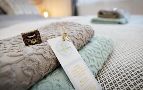 a bed with two pillows and a tag on it at Villa Inda Rooms in Eger