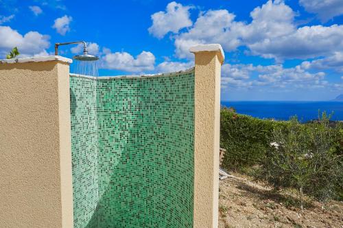 a green tiled wall with the ocean in the background at Villa Ninetta in Scopello