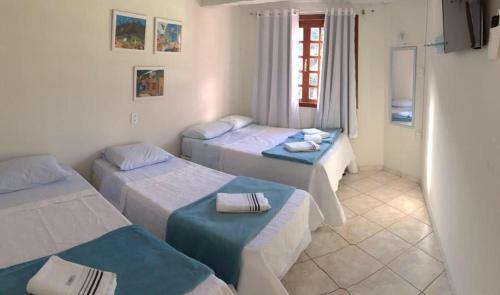 a hotel room with three beds and a window at Hospedaria Aconchego in Santa Teresa