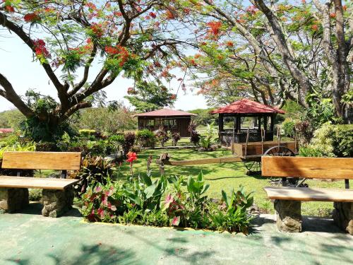a park with two benches and a gazebo at Hotel Rincón de la Vieja Lodge in Liberia