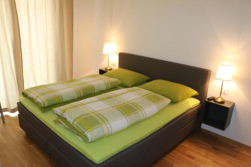 1 cama con 2 almohadas verdes y 2 lámparas en Appartment Larcher - Manzoni, en Merano
