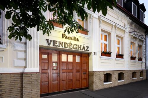a building with wooden doors and a sign on it at Família Vendégház in Szeged