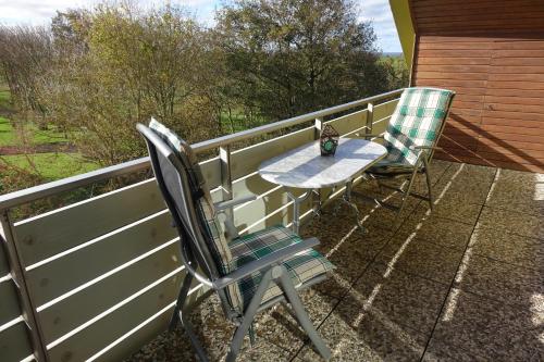 a patio with two chairs and a table on a porch at Grüne Düne Meerblick in Friedrichskoog-Spitz