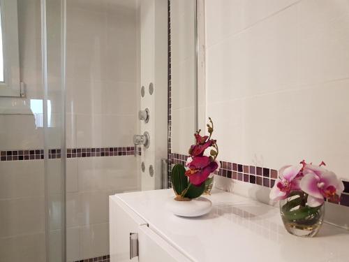 - une salle de bains avec 2 vases et des fleurs sur un comptoir dans l'établissement Appartement Malya & parking privé, à Grenoble