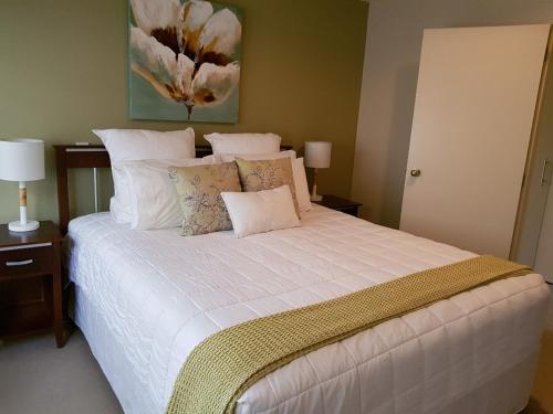ein Schlafzimmer mit einem großen weißen Bett mit Kissen in der Unterkunft Ocean Breeze Resort Pauanui in Pauanui
