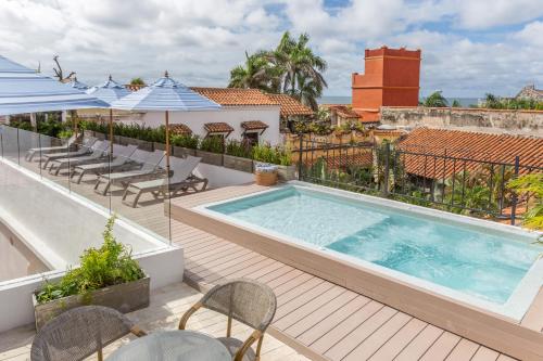a swimming pool on a balcony with chairs and umbrellas at Hotel Casa La Factoria by Faranda Boutique, a member of Radisson Individuals in Cartagena de Indias