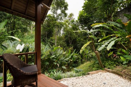 a porch with a chair on a wooden deck at Adiwana Dara Ayu Villas in Payangan
