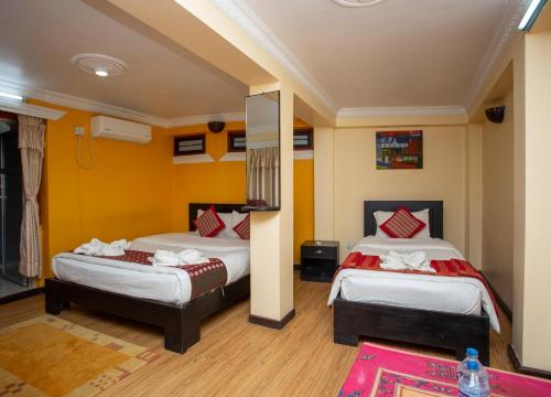 two beds in a room with yellow walls at Kathmandu Boutique Hotel in Kathmandu