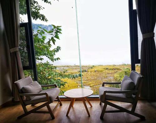 two chairs and a table in front of a large window at Beyond the Terrace Residence in Yuanyang