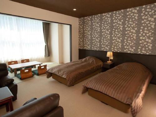 a bedroom with two beds and a table and a couch at Itoen Hotel Bandai Mukaitaki in Koriyama