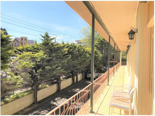 a balcony with chairs and trees on a building at The Clarendon Motel Katoomba in Katoomba