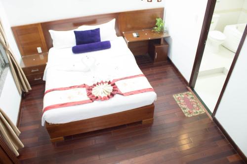 a bedroom with a bed with white sheets and blue pillows at Hoa Phat Hotel & Apartment in Ho Chi Minh City