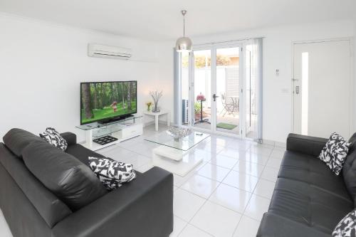 a living room with a black couch and a television at 112 Olive Apartments in Mildura