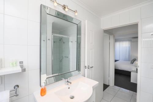 a white bathroom with a sink and a mirror at 112 Olive Apartments in Mildura