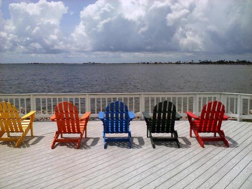 four colorful rocking chairs sitting on a deck near the water at Sailport Waterfront Suites in Tampa