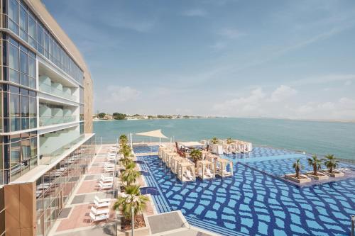 a resort with a pool and chairs and the ocean at Royal M Hotel Abu Dhabi by Gewan in Abu Dhabi