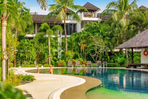 uma piscina de resort com palmeiras e um edifício em Bangtao Beach Garden by RESAVA em Bang Tao Beach