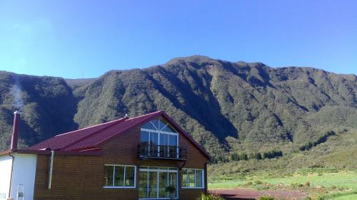 a house with a balcony in front of a mountain at L'Arum des Prairies in Bras des Calumets