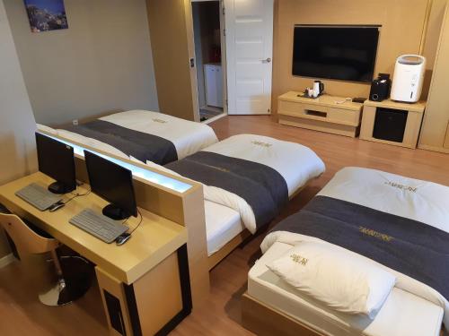 a room with two beds and a desk with a computer at No.1 New Yorker Hotel in Jinju