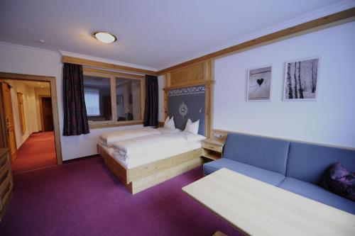ein Hotelzimmer mit einem Bett und einem Sofa in der Unterkunft Hotel Post Kappl in Kappl
