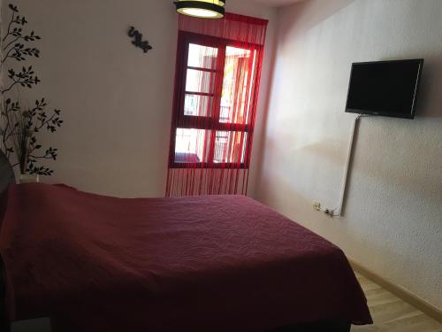 a bedroom with a red bed and a window at Beach Apartment la Arena in Puerto de Santiago