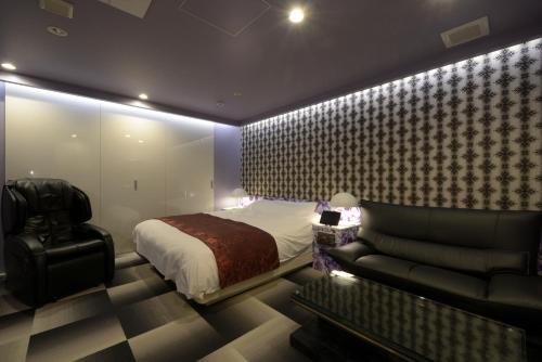 a bedroom with a bed and a couch and a chair at Hotel 5stars (Adult Only) in Takamatsu