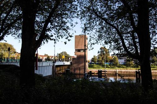a building in the middle of a river with trees at SWEETS - Gerben Wagenaarbrug in Amsterdam