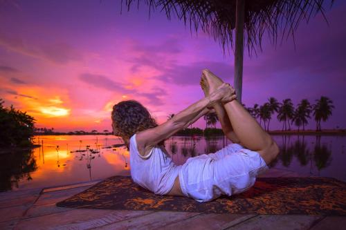 a woman sitting under a palm tree with her legs in the air at Kitesurfing Lanka in Kalpitiya