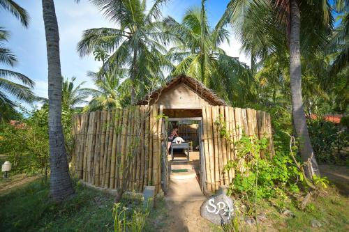 a small building with a person sitting in the doorway at Kitesurfing Lanka in Kalpitiya