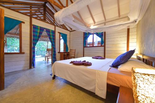 a bedroom with a bed in a room with windows at Kitesurfing Lanka in Kalpitiya