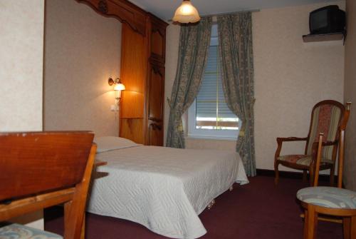 a bedroom with a bed and a desk and a window at Hotel De France in Pontorson
