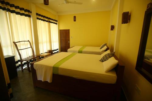 a hotel room with two beds and a chair at Moon Light Guest House in Tissamaharama